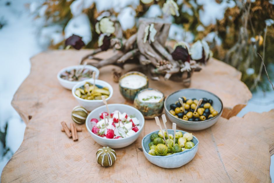 A rustic winter spread of appetizers on a wooden surface, featuring vegetables and dips.