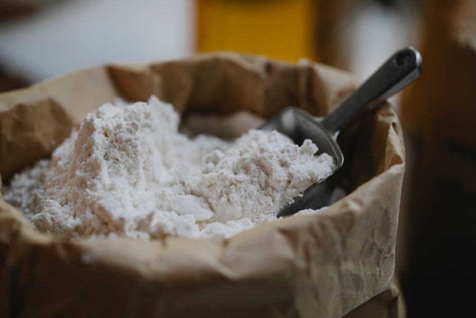 High angle of wheat flour with metal scoop prepared for pastry and cooking process