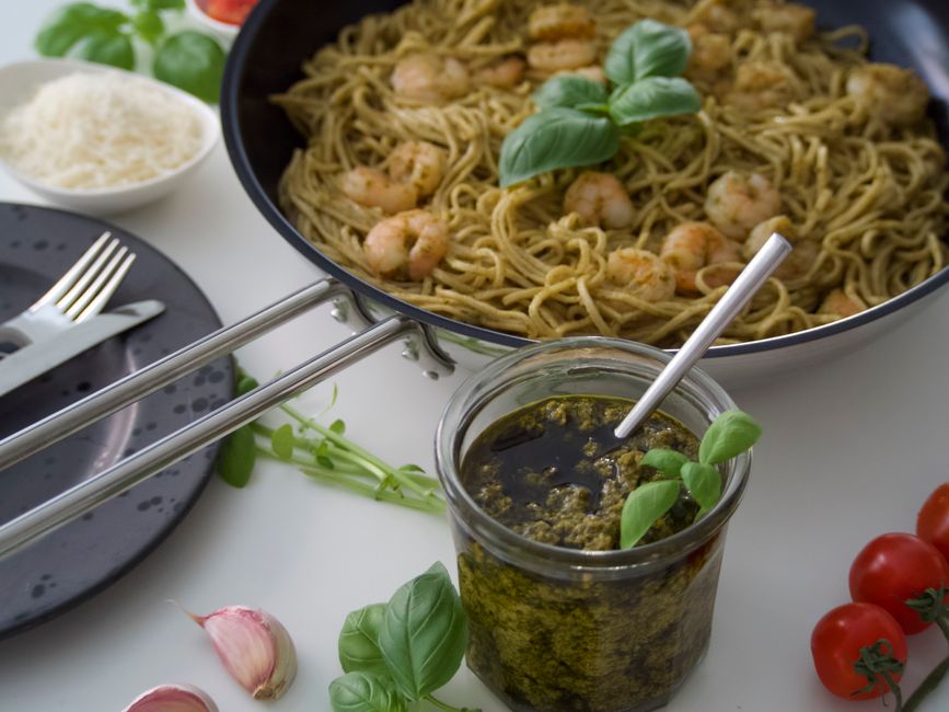 Savor the taste of shrimp pesto pasta garnished with fresh basil and cherry tomatoes.
